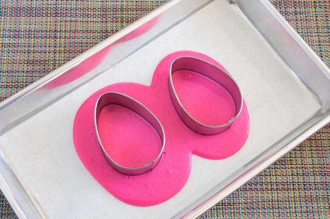 Egg-shaped cookie cutters set into the melted pink coating chocolate | Erin Gardner | Erin Bakes