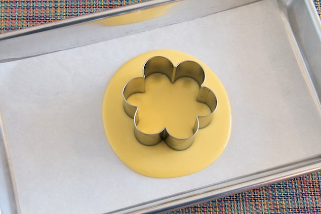 Flower-shaped cookie cutter set into melted yellow coating chocolate | Erin Gardner | Erin Bakes